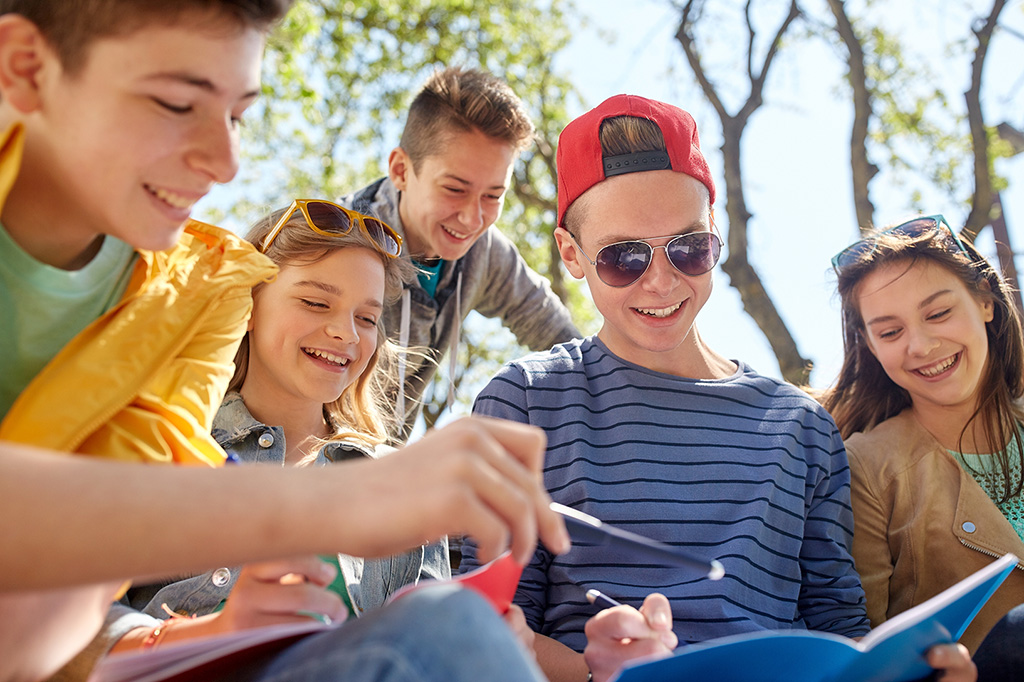 education, high school and people concept - group of happy teenage students with notebooks learning at campus yard